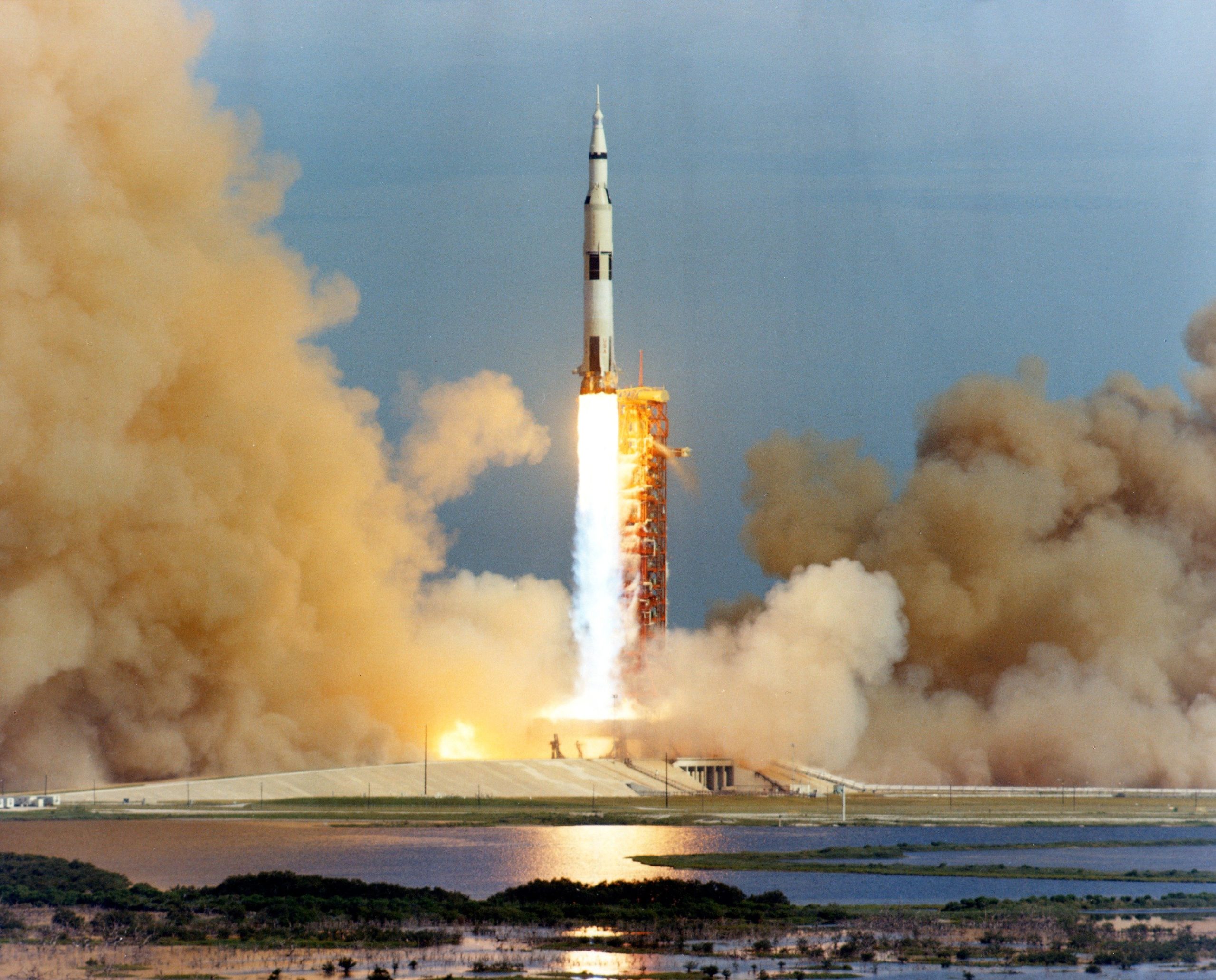 A color photograph with a wise shot of the Apollo 15 lift-off. The Saturn V has just cleared the top of the support structure. "The tower is clear!"